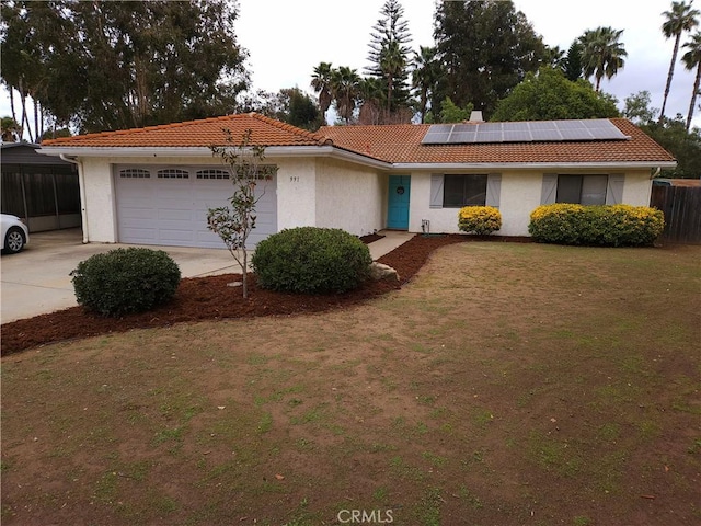 ranch-style house with driveway, a tile roof, fence, roof mounted solar panels, and stucco siding