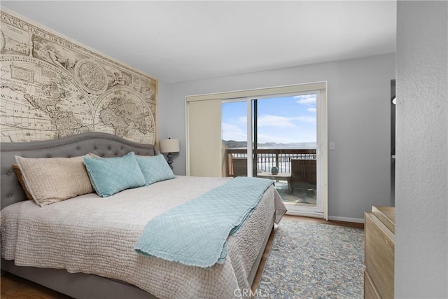 bedroom featuring baseboards, wood finished floors, and access to exterior