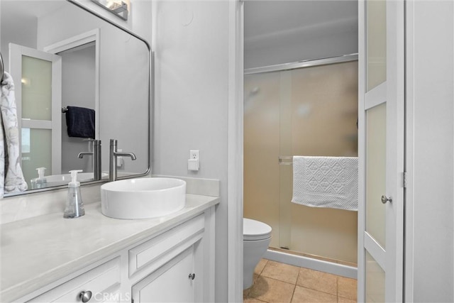 bathroom with a stall shower, vanity, toilet, and tile patterned floors