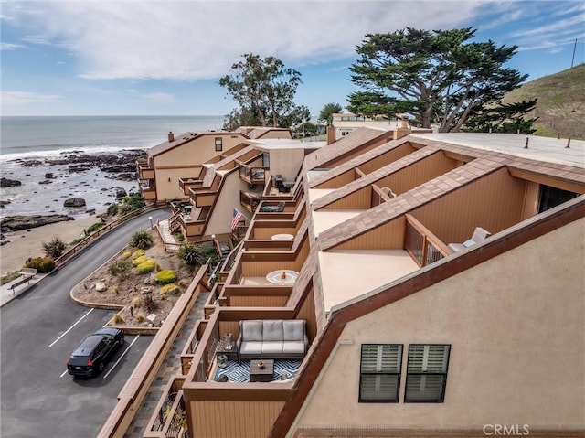 view of property with a water view, uncovered parking, and a beach view