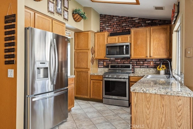 kitchen with lofted ceiling, light tile patterned floors, stainless steel appliances, a sink, and visible vents