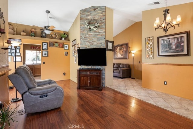 living room with ceiling fan with notable chandelier, lofted ceiling, visible vents, and wood finished floors