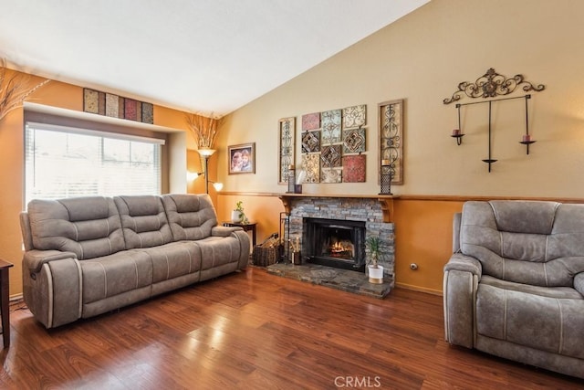 living room with baseboards, vaulted ceiling, wood finished floors, and a stone fireplace