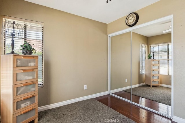 unfurnished bedroom with a closet, baseboards, and hardwood / wood-style flooring