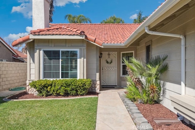 property entrance featuring a yard, fence, and a tiled roof