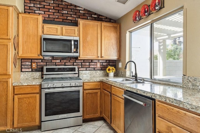 kitchen with light tile patterned floors, stainless steel appliances, lofted ceiling, light countertops, and a sink