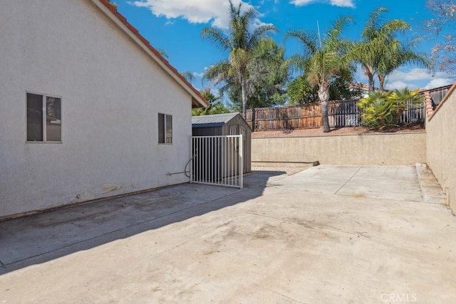 view of patio with a fenced backyard, a storage unit, and an outdoor structure