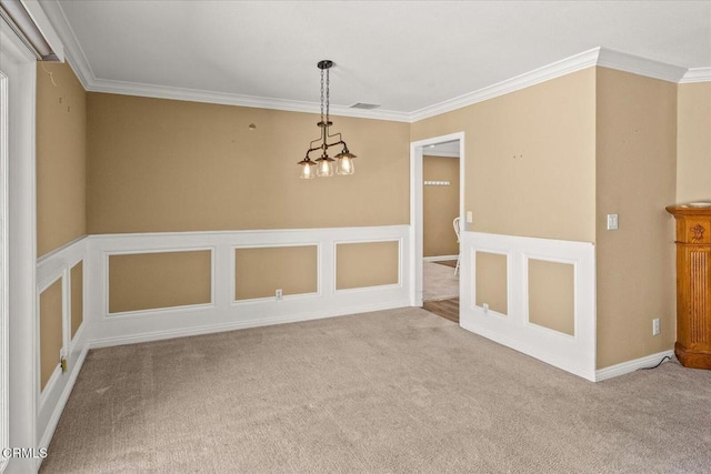 carpeted empty room with a decorative wall, wainscoting, visible vents, and crown molding