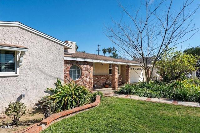 view of front of house with a garage, a front yard, a chimney, and stucco siding