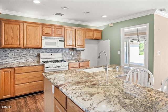 kitchen featuring light stone counters, white appliances, a sink, visible vents, and crown molding