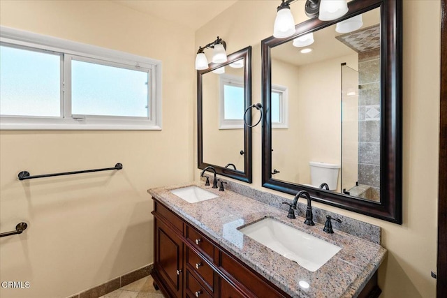 full bathroom with toilet, a sink, baseboards, and double vanity