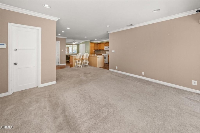 unfurnished living room with crown molding, recessed lighting, visible vents, light carpet, and baseboards