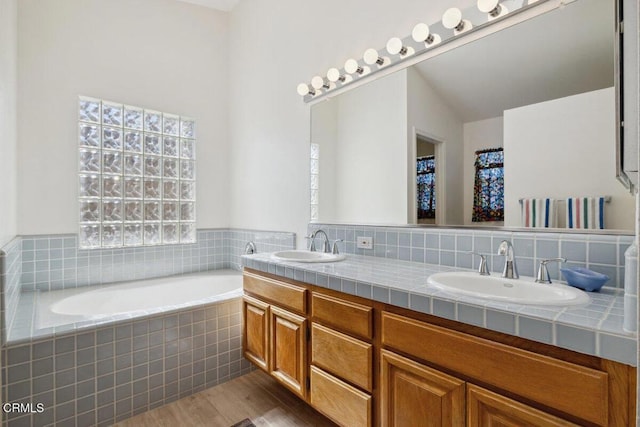 full bathroom featuring double vanity, a garden tub, a sink, and wood finished floors