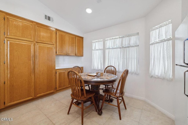 dining room featuring vaulted ceiling, light tile patterned floors, visible vents, and baseboards