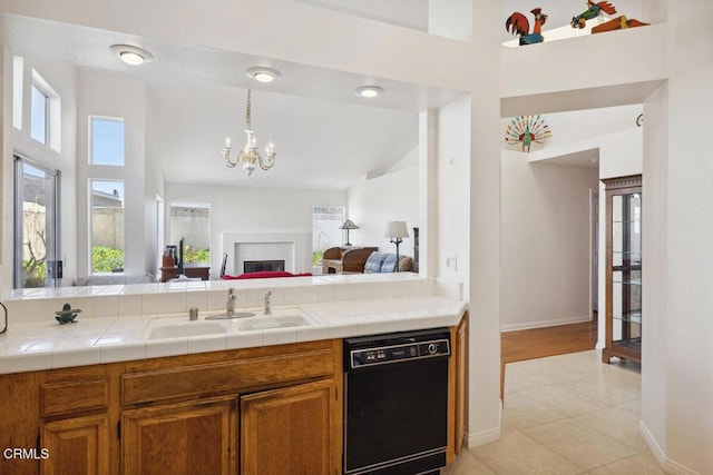 kitchen with dishwasher, brown cabinetry, a sink, and a healthy amount of sunlight