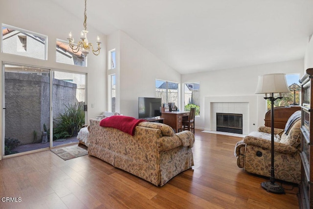 living room featuring high vaulted ceiling, a tile fireplace, wood finished floors, and a healthy amount of sunlight