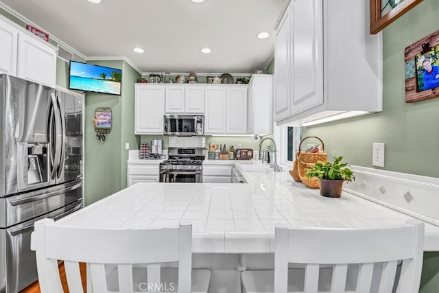 kitchen with stainless steel appliances, a peninsula, tile counters, and white cabinets