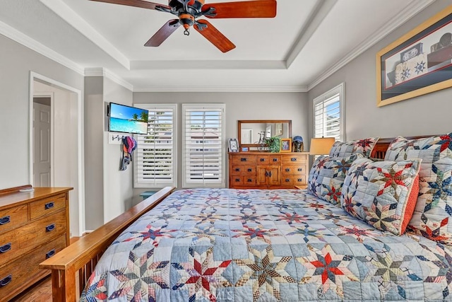 bedroom with ceiling fan, a tray ceiling, and crown molding