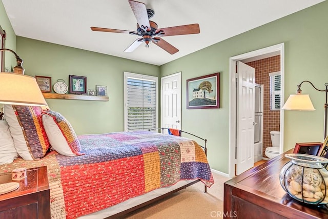 carpeted bedroom with a closet, baseboards, a ceiling fan, and ensuite bathroom