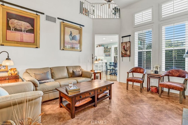 living area featuring a healthy amount of sunlight, a towering ceiling, and visible vents