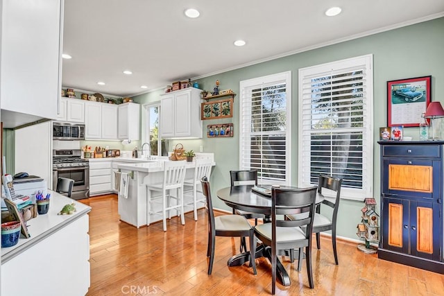 dining area featuring ornamental molding, recessed lighting, and light wood-style flooring