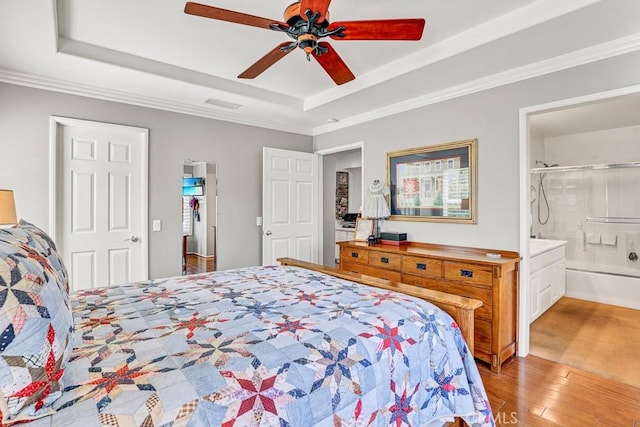 bedroom featuring ceiling fan, wood finished floors, visible vents, a raised ceiling, and crown molding