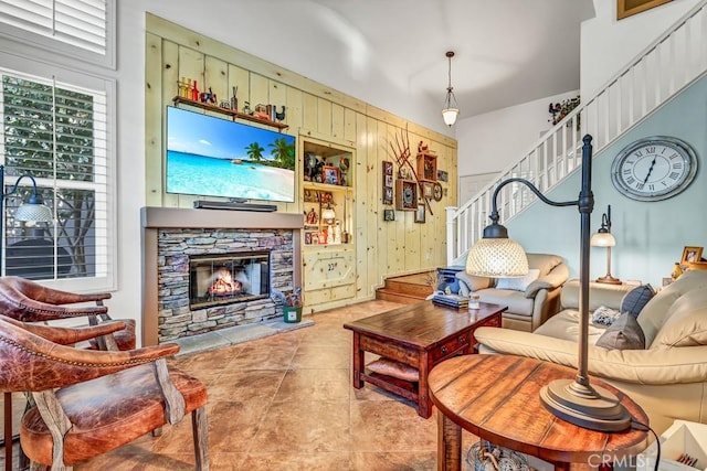 tiled living area with wood walls, stairs, and a fireplace