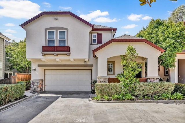 mediterranean / spanish-style home featuring an attached garage, fence, concrete driveway, and stucco siding