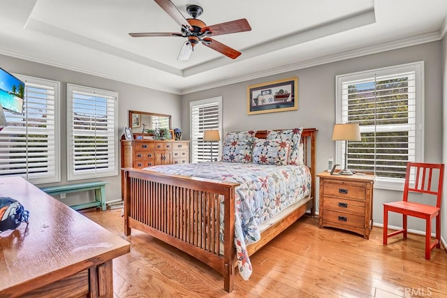 bedroom featuring light wood finished floors, baseboards, a raised ceiling, a ceiling fan, and ornamental molding