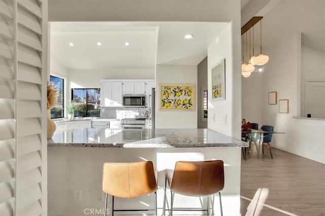 31 Blue River Dr, Palm Desert, CA 92211 - kitchen featuring appliances with stainless steel finishes, white cabinets, light wood finished floors, a peninsula, and light stone counters