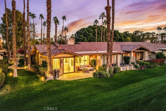 31 Blue River Dr, Palm Desert, CA 92211 - back of property at dusk featuring a patio area, a yard, stucco siding, and a chimney