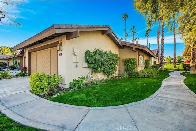 31 Blue River Dr, Palm Desert, CA 92211 - view of property exterior with an attached garage, a yard, concrete driveway, and stucco siding