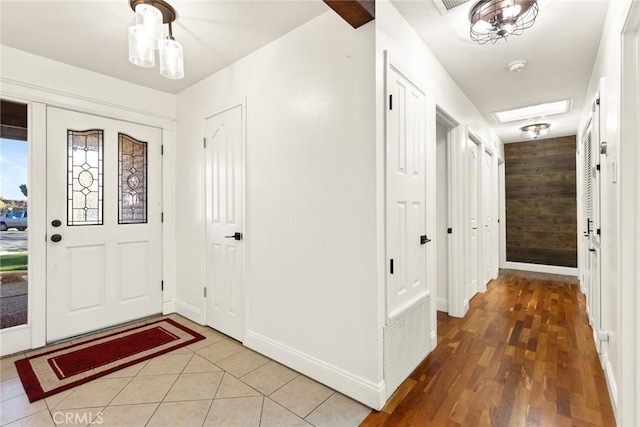 foyer featuring wooden walls, light tile patterned flooring, and baseboards