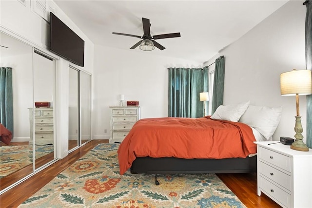 bedroom featuring dark wood-type flooring, multiple closets, and a ceiling fan