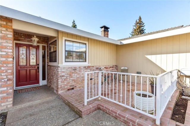 doorway to property featuring brick siding and a chimney