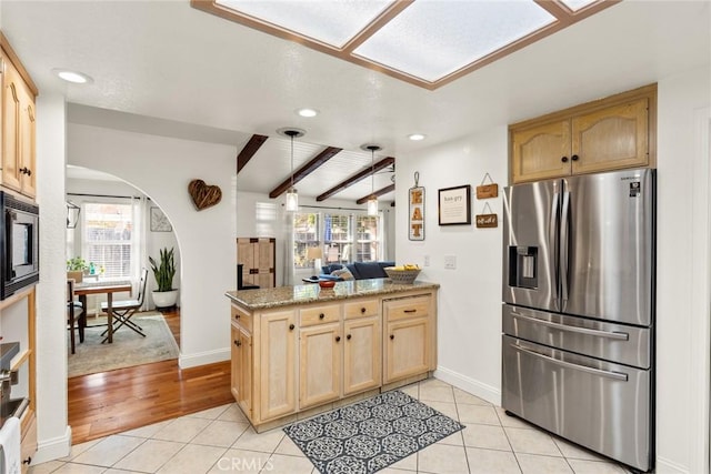 kitchen featuring light tile patterned floors, light brown cabinets, a peninsula, stainless steel fridge with ice dispenser, and built in microwave