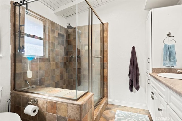 bathroom with toilet, a stall shower, vanity, baseboards, and tile patterned floors