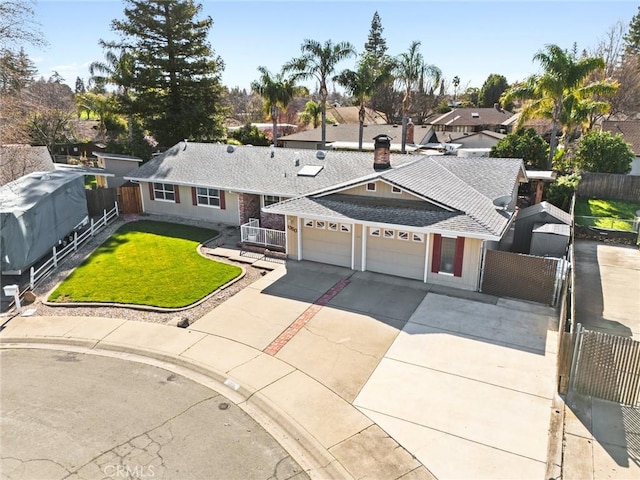 view of front of home with concrete driveway, fence, a front lawn, and an attached garage