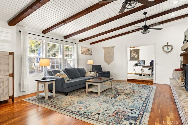 living area with lofted ceiling with beams, wood finished floors, a ceiling fan, and baseboards