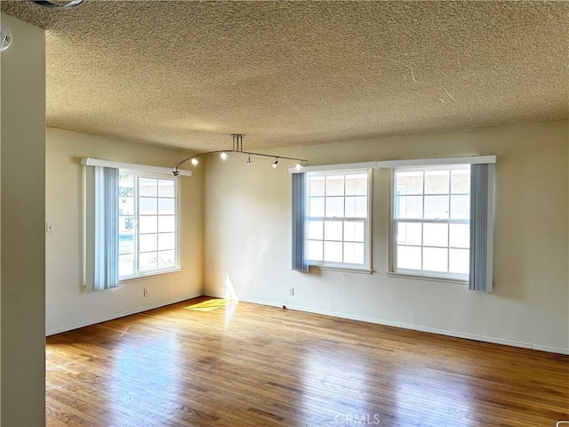 unfurnished room featuring a textured ceiling, baseboards, and wood finished floors