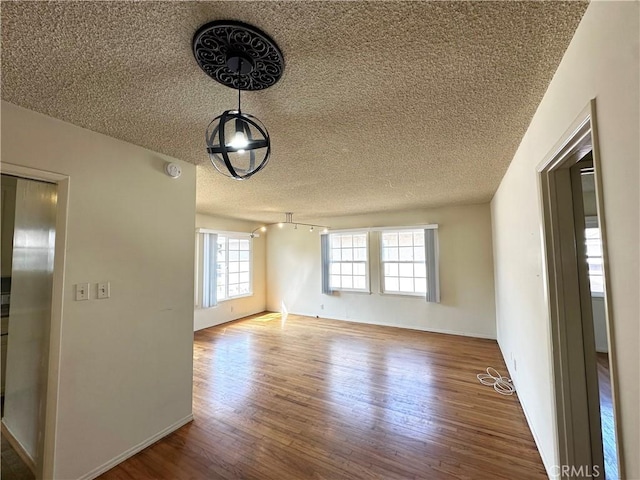 empty room with a textured ceiling and wood finished floors