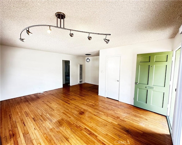 spare room with light wood-type flooring and a textured ceiling