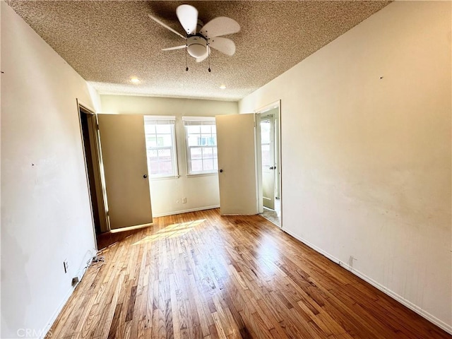 spare room with a ceiling fan, a textured ceiling, baseboards, and wood finished floors