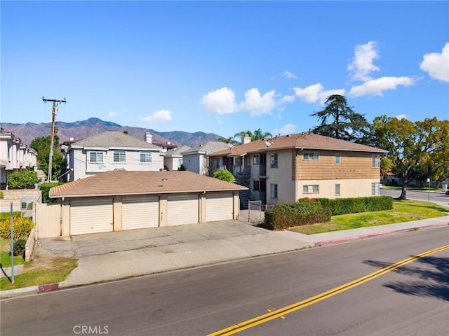 view of front of home featuring a residential view, fence, a mountain view, and community garages