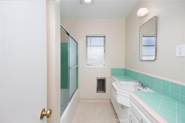 bathroom featuring heating unit, tile patterned flooring, combined bath / shower with glass door, and vanity