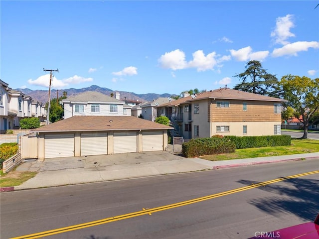 view of front facade featuring a mountain view, a residential view, and community garages