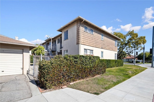 view of side of home featuring a garage, a yard, and stucco siding