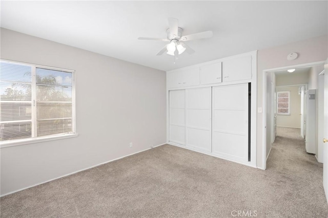 unfurnished bedroom featuring a closet, light carpet, and ceiling fan