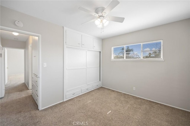 unfurnished bedroom with a closet, a ceiling fan, and light colored carpet