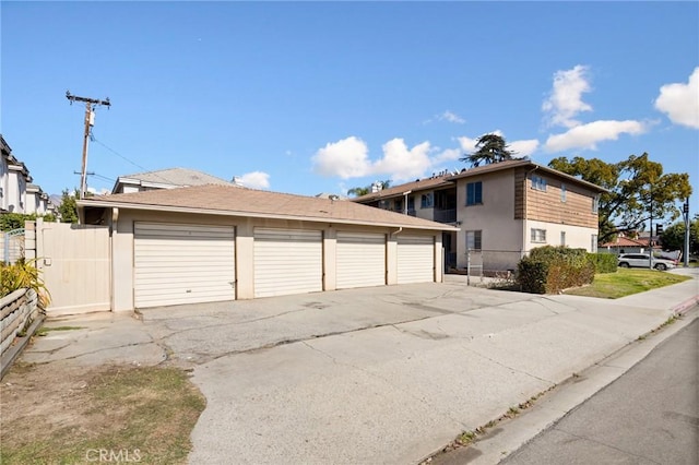 view of front of home with stucco siding, fence, and community garages